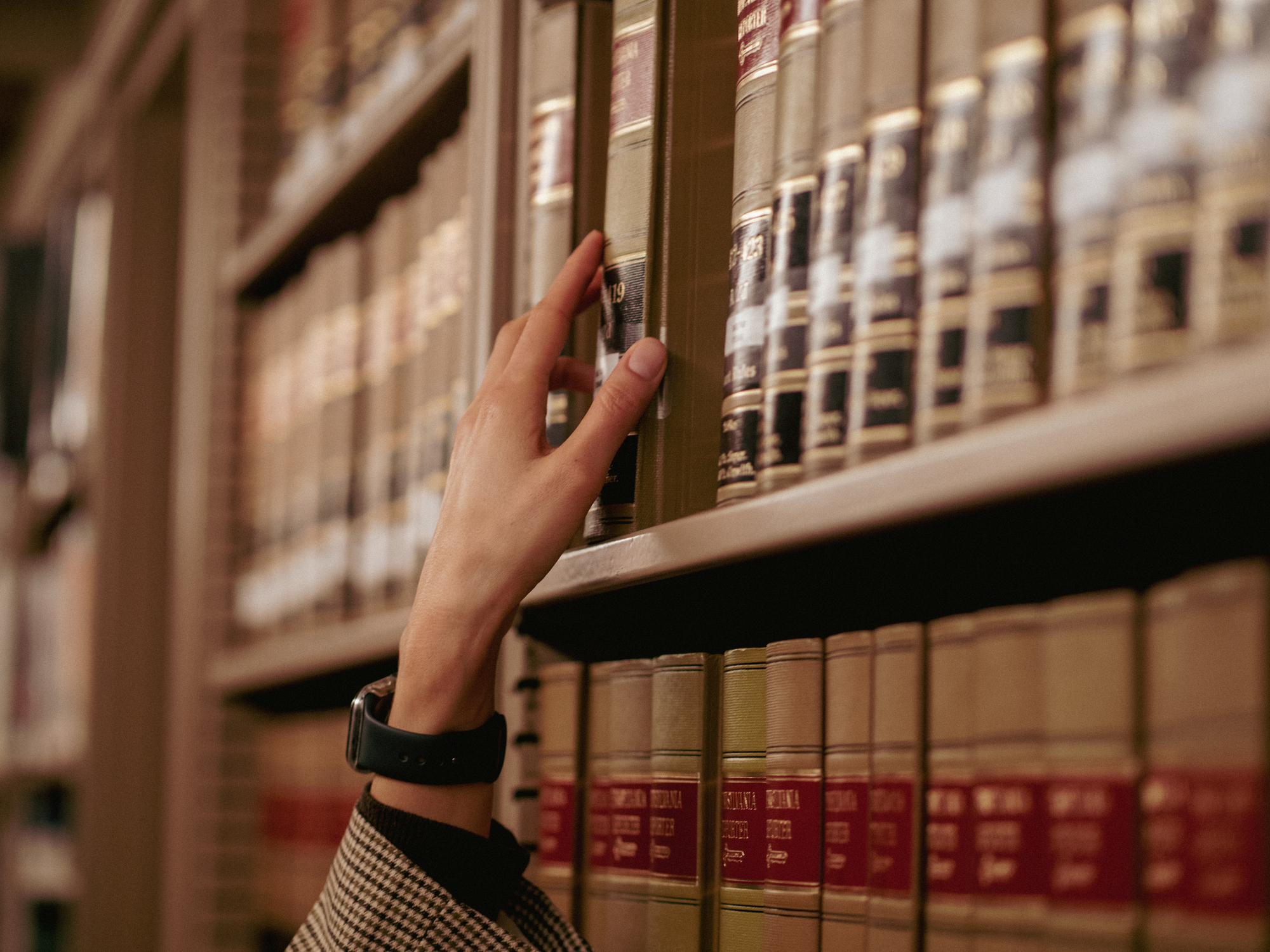 Personne tendant la main pour prendre un livre dans une bibliothèque